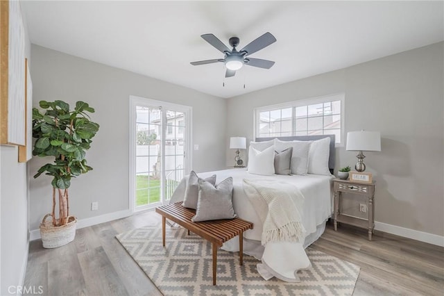 bedroom featuring baseboards, multiple windows, and wood finished floors