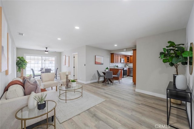 living area with recessed lighting, light wood-style flooring, a ceiling fan, and baseboards