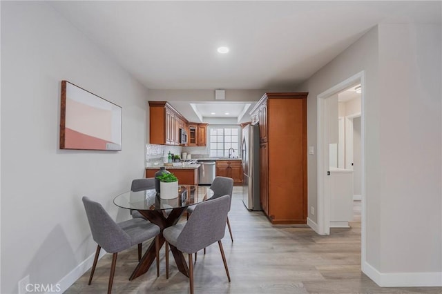 dining room with recessed lighting, light wood-style floors, and baseboards