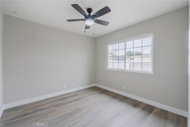 spare room featuring ceiling fan, baseboards, and wood finished floors