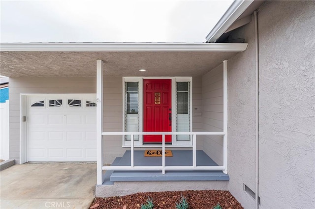 doorway to property featuring crawl space, stucco siding, driveway, and a garage