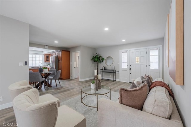 living room featuring light wood-style flooring, recessed lighting, and baseboards