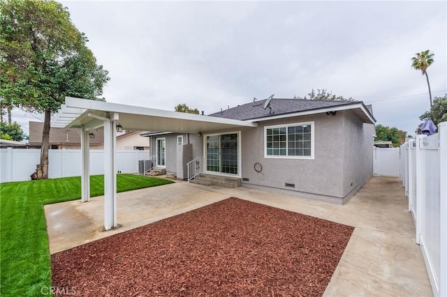 rear view of house featuring stucco siding, a lawn, entry steps, a fenced backyard, and crawl space