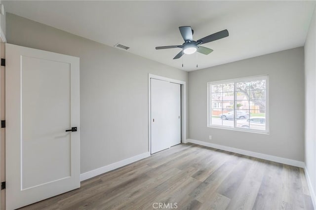 unfurnished bedroom featuring wood finished floors, baseboards, and visible vents