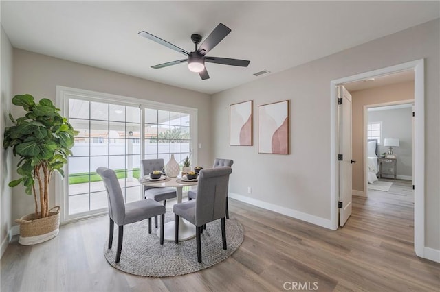 dining area with a ceiling fan, baseboards, visible vents, and light wood-type flooring