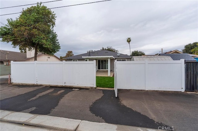 uncovered parking lot with a fenced front yard and a gate