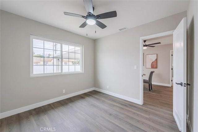 spare room featuring visible vents, baseboards, and wood finished floors