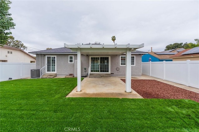 rear view of property featuring stucco siding, a lawn, entry steps, a fenced backyard, and a patio area