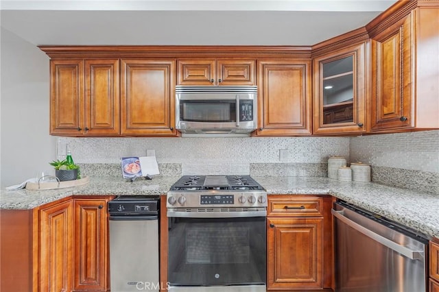 kitchen with backsplash, appliances with stainless steel finishes, and brown cabinetry