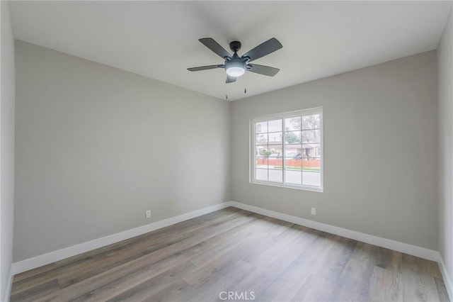 empty room featuring baseboards, wood finished floors, and a ceiling fan