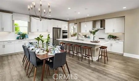 dining space with light wood-style flooring, a notable chandelier, recessed lighting, and baseboards