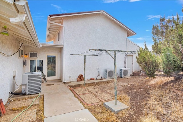 rear view of house featuring stucco siding, a patio, central AC, and ac unit