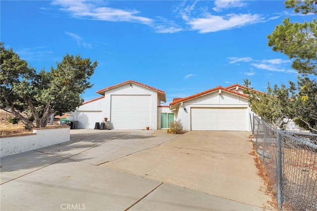 view of front of house with stucco siding, a tile roof, driveway, and fence