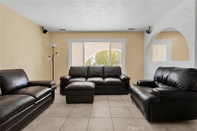 living room with visible vents, a textured ceiling, and light tile patterned flooring