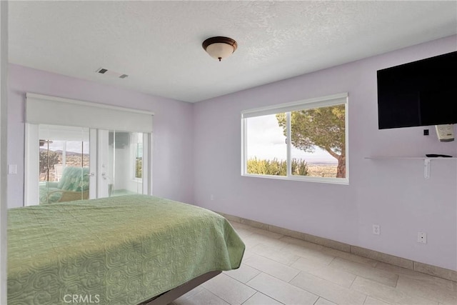 bedroom featuring light tile patterned floors, visible vents, a textured ceiling, and baseboards