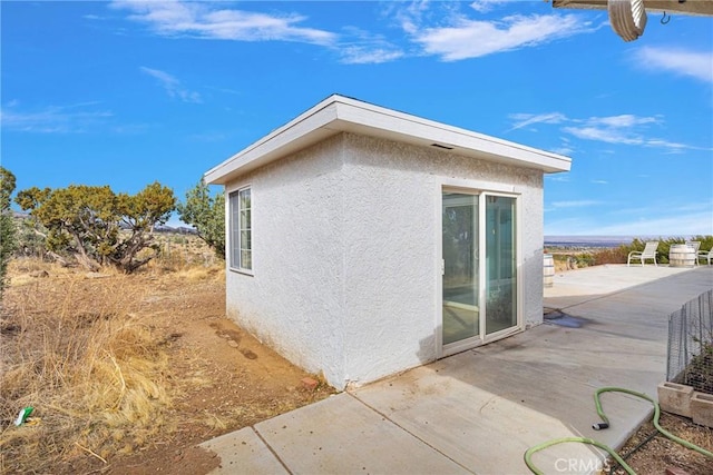 view of home's exterior featuring a patio area, stucco siding, and an outbuilding