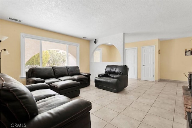 living area with light tile patterned flooring, visible vents, a textured ceiling, and baseboards