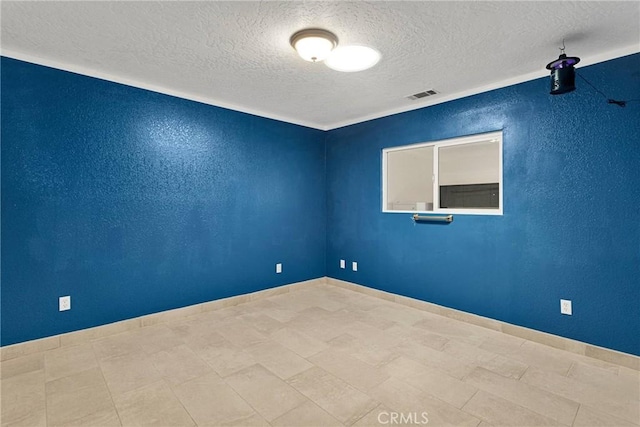 empty room with baseboards, a textured wall, visible vents, and a textured ceiling