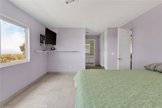 bedroom featuring tile patterned floors, baseboards, and connected bathroom