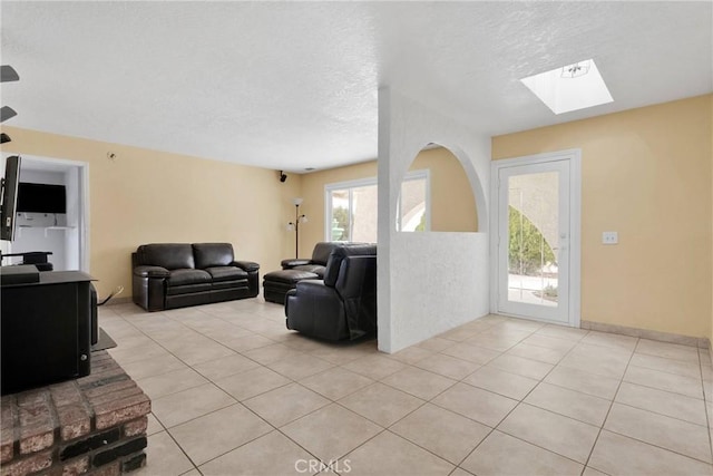 living room featuring a skylight, light tile patterned flooring, and a textured ceiling