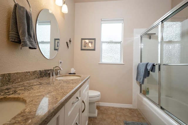 bathroom with tile patterned flooring, baseboards, toilet, double vanity, and a sink