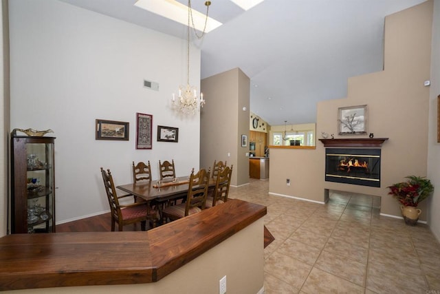 dining room featuring tile patterned flooring, visible vents, baseboards, a chandelier, and a glass covered fireplace