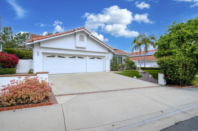 view of front of property with stucco siding, a tile roof, fence, concrete driveway, and an attached garage