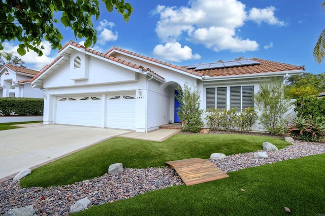 view of front facade featuring an attached garage, a front lawn, a tile roof, roof mounted solar panels, and driveway