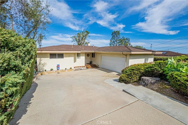 single story home featuring concrete driveway, an attached garage, and stucco siding