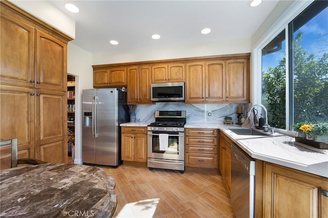 kitchen with backsplash, brown cabinetry, appliances with stainless steel finishes, and a sink