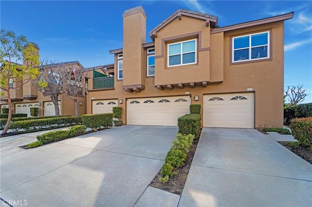 view of property with stucco siding, a garage, and driveway