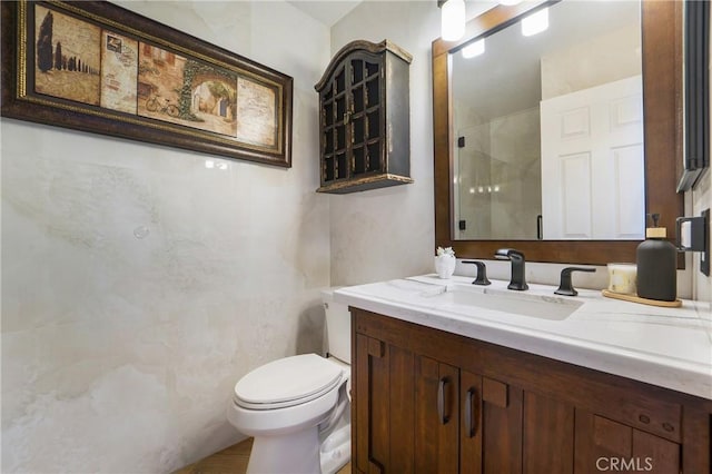 full bathroom featuring toilet, a walk in shower, and vanity