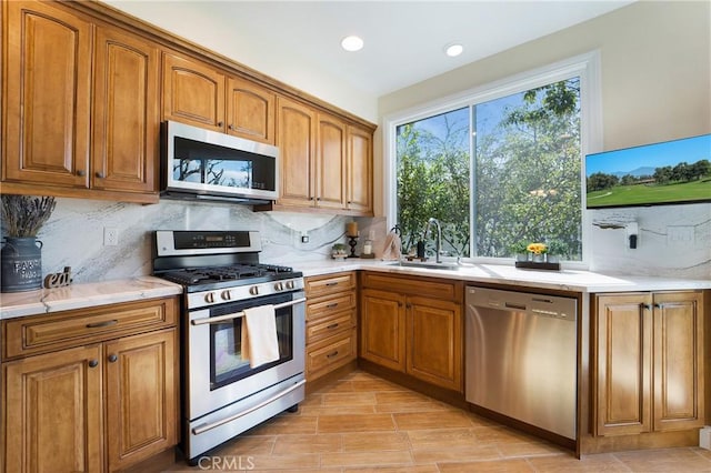 kitchen with backsplash, brown cabinetry, appliances with stainless steel finishes, and a sink