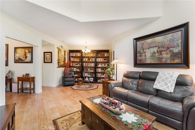 living room with a chandelier, light wood-type flooring, and baseboards