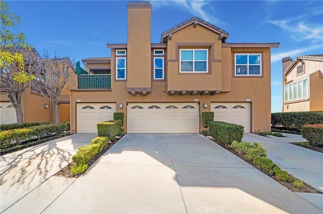 view of property with stucco siding, concrete driveway, and an attached garage