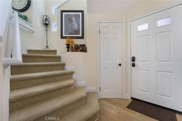 entryway with baseboards, stairs, and light wood-style floors