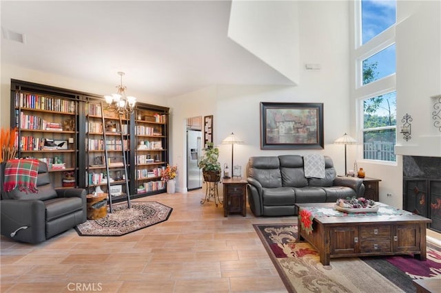 living area with a notable chandelier, a tile fireplace, visible vents, and a towering ceiling