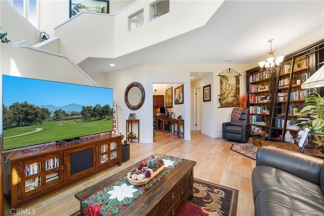 living room with a notable chandelier, a high ceiling, baseboards, and wood finished floors