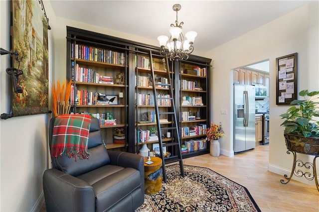 sitting room featuring an inviting chandelier, light wood-style floors, and baseboards