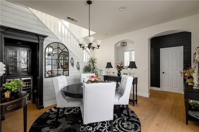 dining area featuring a notable chandelier, arched walkways, visible vents, and light wood finished floors