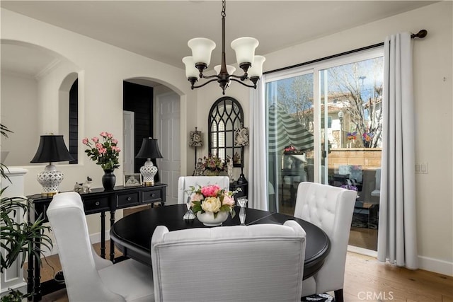 dining area with baseboards, an inviting chandelier, and wood finished floors