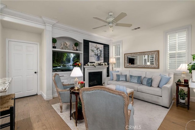 living area with visible vents, a ceiling fan, wood finished floors, and a fireplace