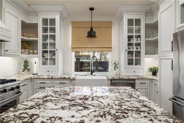 kitchen with light stone countertops, stainless steel appliances, glass insert cabinets, and a sink