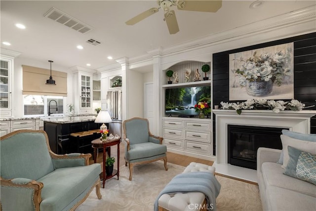 living room featuring visible vents, ornamental molding, and a glass covered fireplace