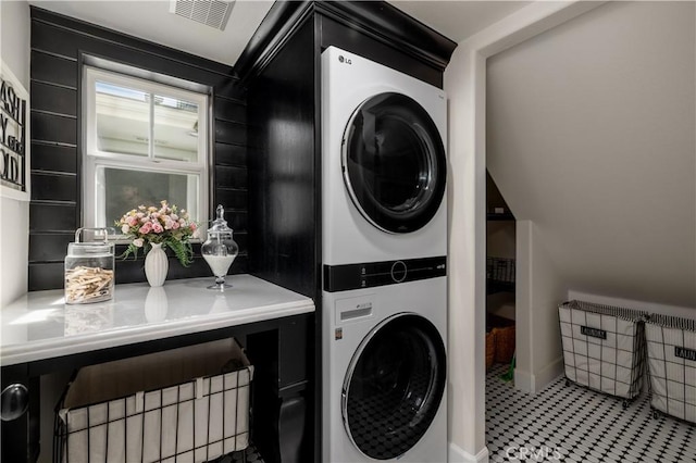 washroom with stacked washer / dryer, laundry area, and visible vents