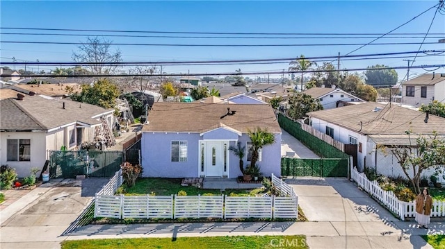 view of front facade with a fenced front yard, a residential view, driveway, and stucco siding