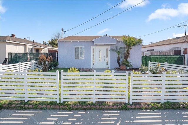 bungalow-style house featuring a fenced front yard and stucco siding