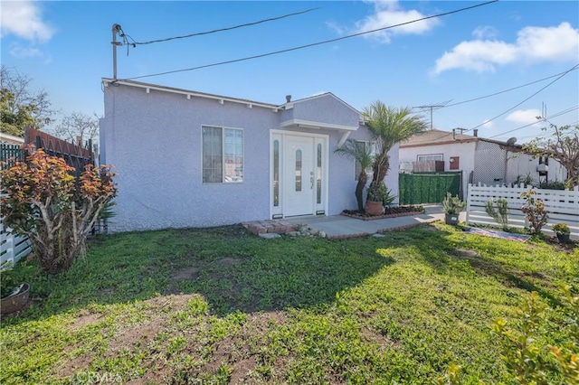 view of front of property featuring stucco siding, a front yard, and fence