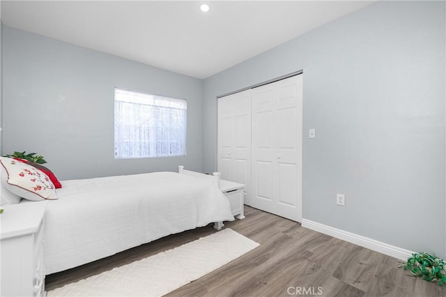 bedroom with a closet, baseboards, and light wood-style flooring