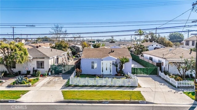 view of front of house with a fenced front yard, a residential view, stucco siding, and concrete driveway